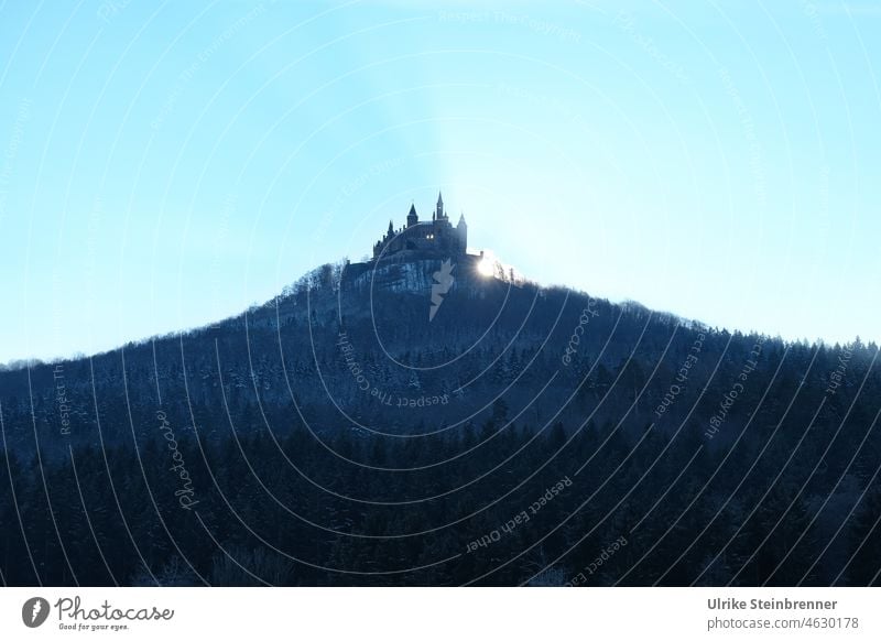 Winterliche Morgensonne geht hinter der Burg Hohenzollern auf Sonnenaufgang Burgberg Wintermorgen Sonnenstrahlen Wald Licht Stammburg Preußen Bergkegel