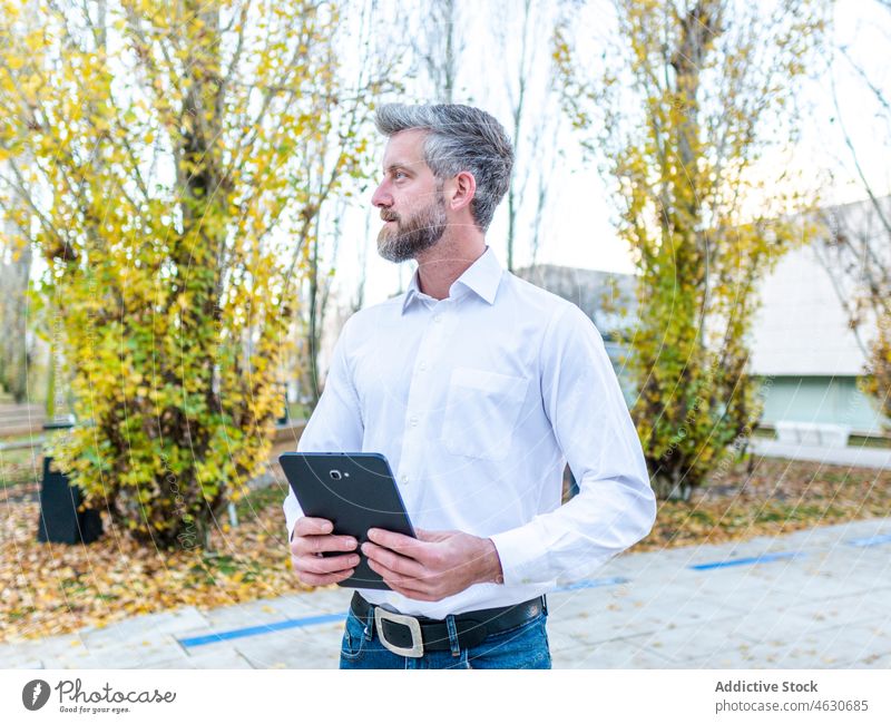 Mann surft auf der Straße auf seinem Tablet Tablette Browsen online Talkrunde Zaun soziale Netzwerke Großstadt Gebäude männlich Vollbart Stil modern Apparatur