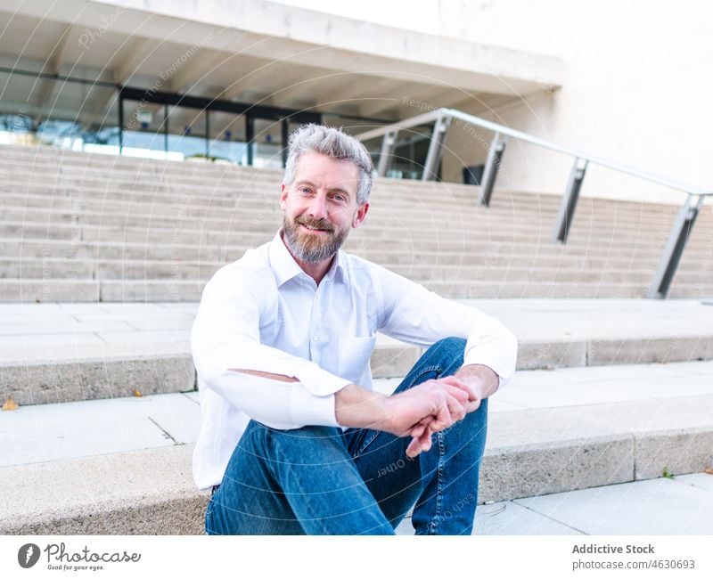 Positiver Geschäftsmann auf einer städtischen Treppe sitzend Mann Unternehmer Treppenhaus Großstadt Straße elegant urban korporativ Business Gebäude Arbeiter