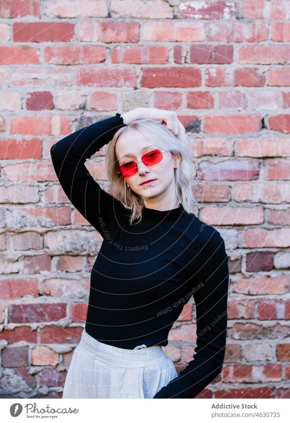 Stilvolle Frau in der Nähe von Ziegelmauer Design Backsteinwand Mode Sonnenbrille feminin trendy Straße attraktiv Großstadt jung Dame Linse Wand Licht Blondine