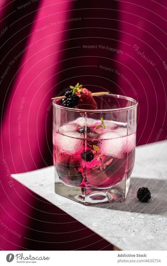 Glas Brombeer-Cocktail mit Eiswürfeln Brombeeren Erfrischung Himbeeren Kristalle Getränk Aperitif kalt Zahnstocher Tisch liquide hölzern cool Schnaps Portion