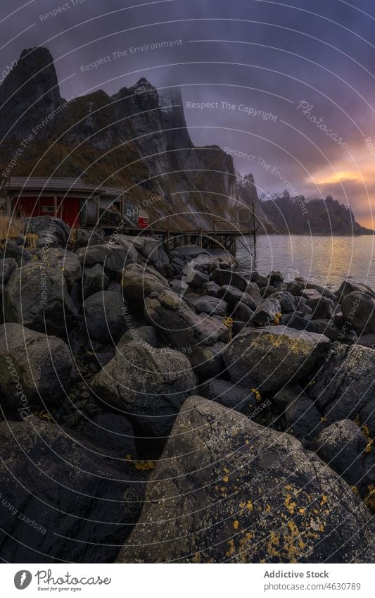 Steinkai in der Nähe der Siedlung bei Sonnenuntergang Pier MEER Dorf Berge u. Gebirge Abend Wasser Windstille Winter kalt lofoten Norwegen Reine Kamm Haus Ufer