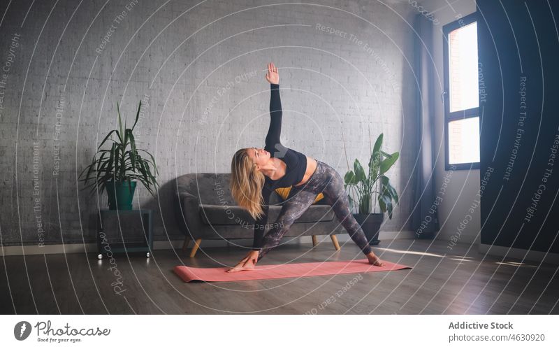 Schlanke Frau in Dreieckspose übt Yoga Triangel-Pose Übung Geist Training mental Gesunder Lebensstil sportlich Aktivität trikonasana Körperhaltung Wellness