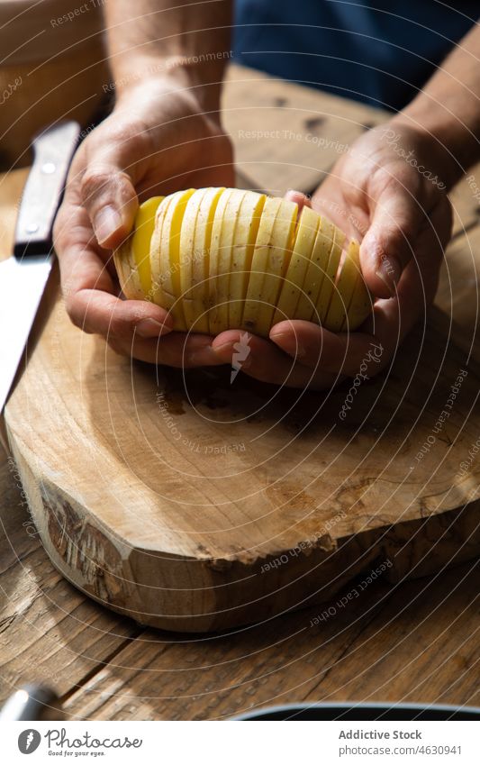 Gesichtsloser Mann zeigt aufgeschnittene Kartoffel Scheibe Koch kulinarisch Küche Gemüse roh hasselback Lebensmittel Produkt Bestandteil Tisch Gastronomie