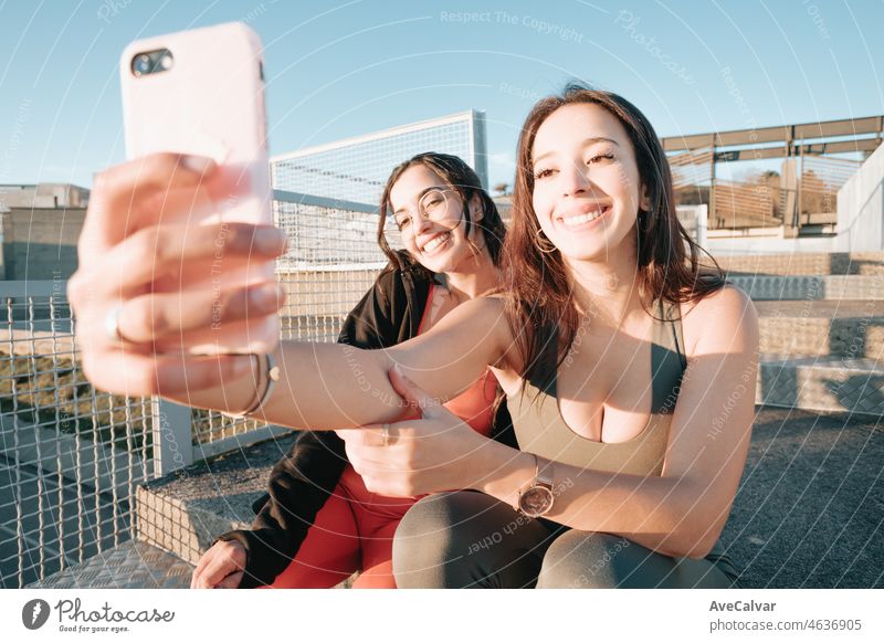 Zwei hübsche junge sportliche afrikanische Frauen, die ein Selfie nach dem Training für soziale Medien mit einem Smartphone machen. Gesunder sportlicher Lebensstil Konzept. Gemeinsam trainieren und Spaß im Freien haben