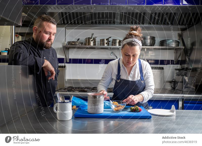 Fröhliche Köche beim gemeinsamen Kochen des Desserts Küchenchef Zusammensein Restaurant Kollege zusammenarbeiten professionell Mann Frau Schalen & Schüsseln