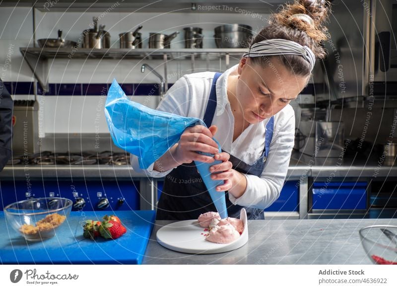 Frau drückt Sahne auf Dessert Küchenchef dekorieren Teller Backwarenbeutel drücken Restaurant Koch vorbereiten Arbeit süß lecker professionell Portion Speise