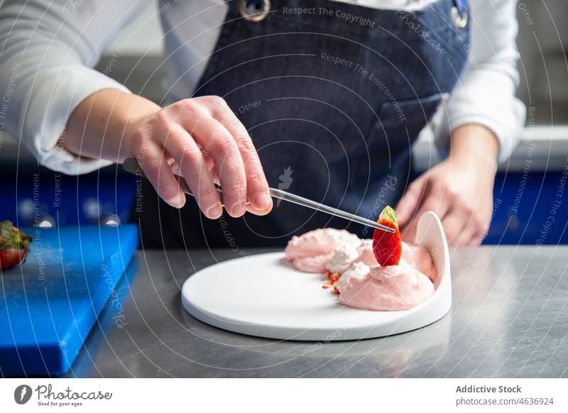 Anonyme Köchin garniert Dessert mit Erdbeere Frau Küchenchef Garnierung Erdbeeren Sahne gepeitscht Restaurant Koch Lebensmittel vorbereiten Schürze frisch