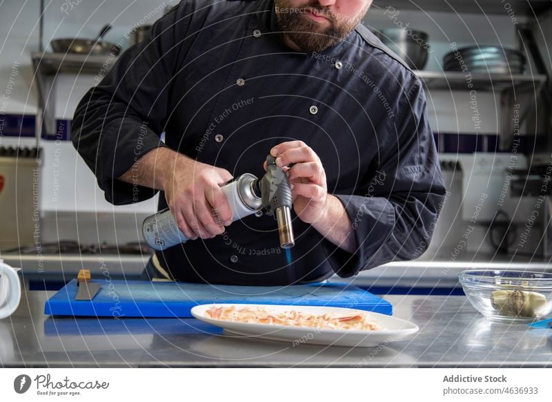 Crop Chef brennt Scheiben von Schweinefleisch Mann Brenner Koch Restaurant Küche Küchenchef Feuer Brandwunde Uniform männlich professionell Job Arbeit