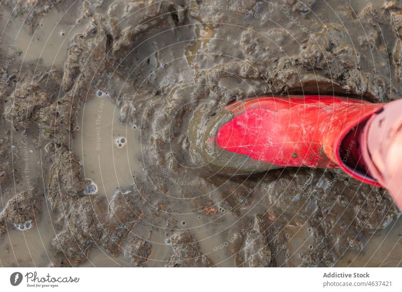 Anonymes Kind steht auf schmutzigem Boden Weg Gummistiefel Schmutz Schlamm Pfütze nass Wasser Straße Kindheit Stiefel dreckig Bürgersteig Farbe Laufsteg hell