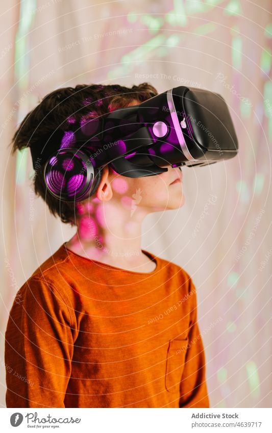 Junge erkundet den Cyberspace mit VR-Brille Kind Virtuelle Realität erkunden Erfahrung Schutzbrille Headset virtuell neonfarbig Apparatur Gerät Innovation