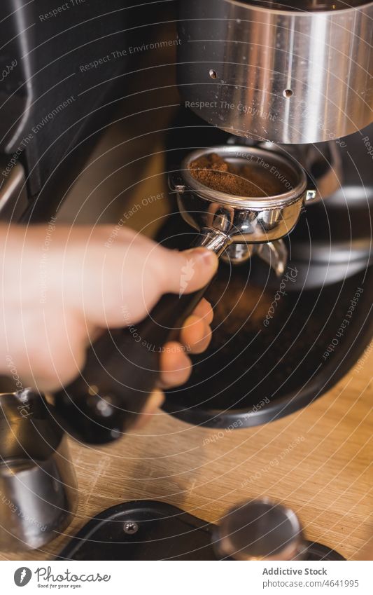 Barista beim Einsetzen des Siebträgers in die Edelstahl-Kaffeemühle Portafilter Schleifmaschine Boden frisch Maschine Vorrichtung Kaffeehaus vorbereiten