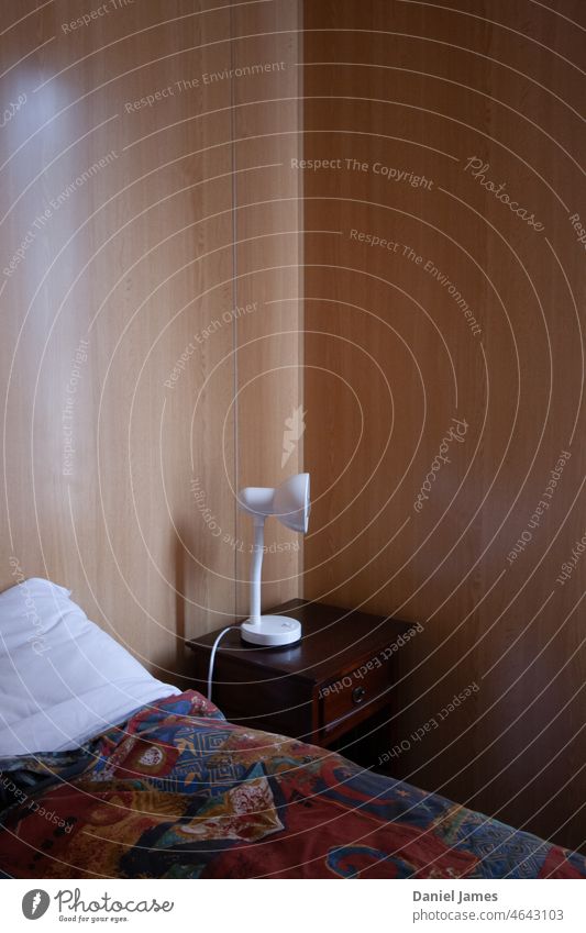 In der Ecke Schlafzimmer Bett Beistelltisch Lampe Licht kahl Ebene karg wertlos Eckstoß Holzvertäfelung günstiger Urlaub Raum einfach Möbel Wohnung