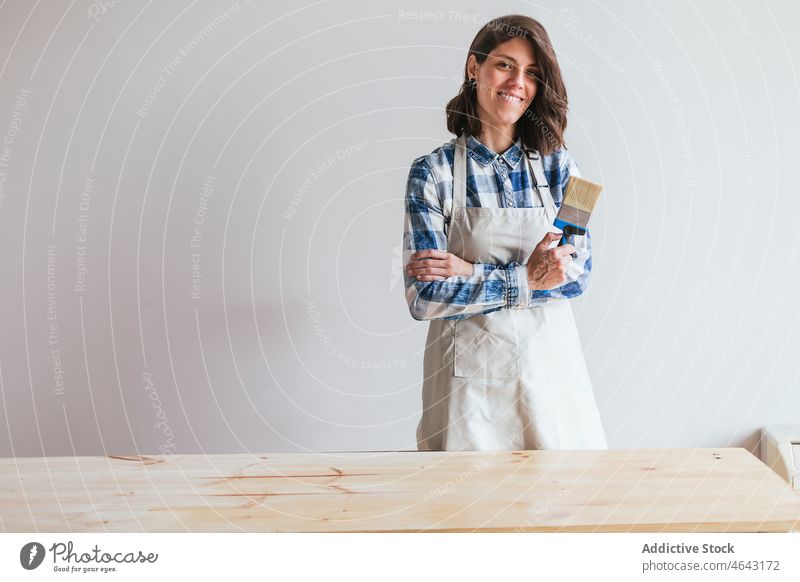 Glückliche Frau mit Pinsel neben Holzbrett Tischlerin beenden Belag Holzarbeiten Werkstatt Arbeit hölzern Holzplatte Bürste Schiffsplanken Herstellung