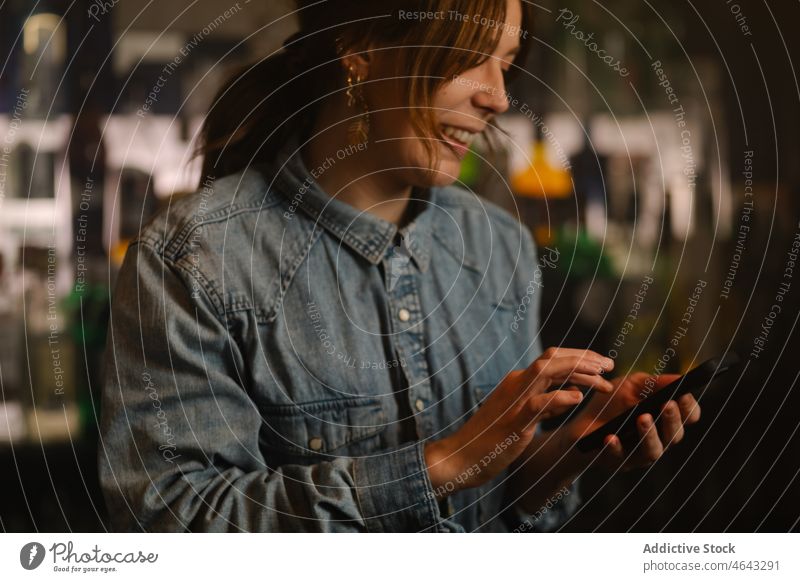 Zufriedener Barkeeper beim Surfen auf dem Smartphone in der Bar Frau Browsen online Internet Arbeit Café Alkohol Arbeiter Arbeitstag Anschluss soziale Netzwerke