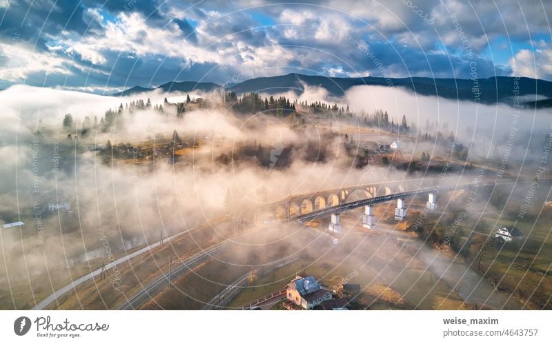 Herbstmorgen, nebliges Bergtal. Eisenbahnbrücke, altes Viadukt in Vorohta. Dorf auf Hügeln von Wolken bedeckt. Berge u. Gebirge Nebel Morgen Brücke Hütte Haus