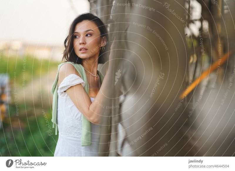 Asiatische Frau in weißem Kleid und grünen Gummistiefeln, die in der Nähe eines Tabaktrockenschuppens posiert. Landschaft Mädchen hübsch Menschen Natur Mode