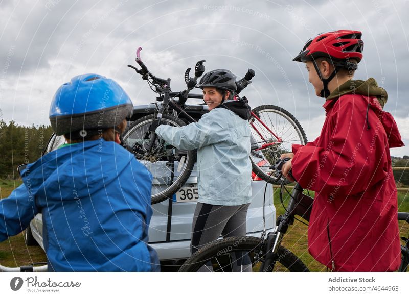 Frau mit Kindern nimmt Fahrrad aus dem Kofferraum Mutter PKW Landschaft Ablage Hobby Aktivität Zeitvertreib Reise Autoreise Natur Jungen Mutterschaft