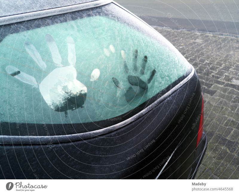 Abdruck von Kinderhänden auf der durch Raureif vereisten Heckscheibe eines alten Auto im Winter in Oerlinghausen bei Bielefeld am Hermannsweg im Teutoburger Wald in Ostwestfalen-Lippe