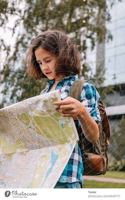 Hipster junges Mädchen schaut auf die Karte. Nettes brünettes Teenie-Mädchen reist im Sommerurlaub. Vertikale Aufnahme Blick Landkarte niedlich Teenager-Mädchen