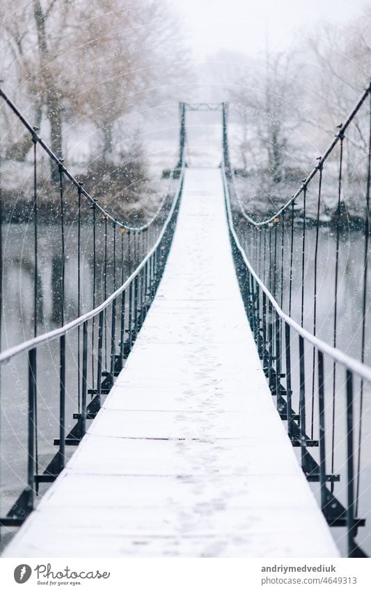 Fußgänger-Hängebrücke aus Stahl und Holz über den Fluss, Winter Brücke Landschaft Weg erhängen Wald Steg reisen Natur Ansicht hölzern hängend Park Schnee