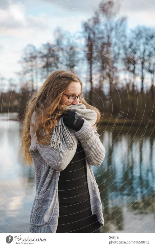 Eine junge frierende Frau mit Brille und langen Haaren in einen Schal gewickelt. Winter Kälte lange Haare Lifestyle Außenaufnahme kalt Herbst Erwachsene lässig