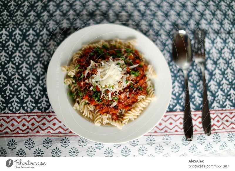 Suppenteller mit Spirelli/Fusilli und Sauce Bolognese mit Parmesankäse und frischem Basilikum Tischdecke Muster Teller Besteck Gabel Löffel Porzellan Pasta