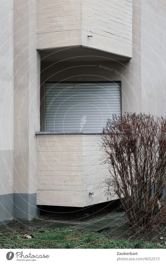 Balkon, geschlossener Rolladen und Fassade eines tristen Wohnhauses Wohnung grau Strauch Stadt wohnen einsam städtisch Fenster Haus Architektur mietshaus eckig