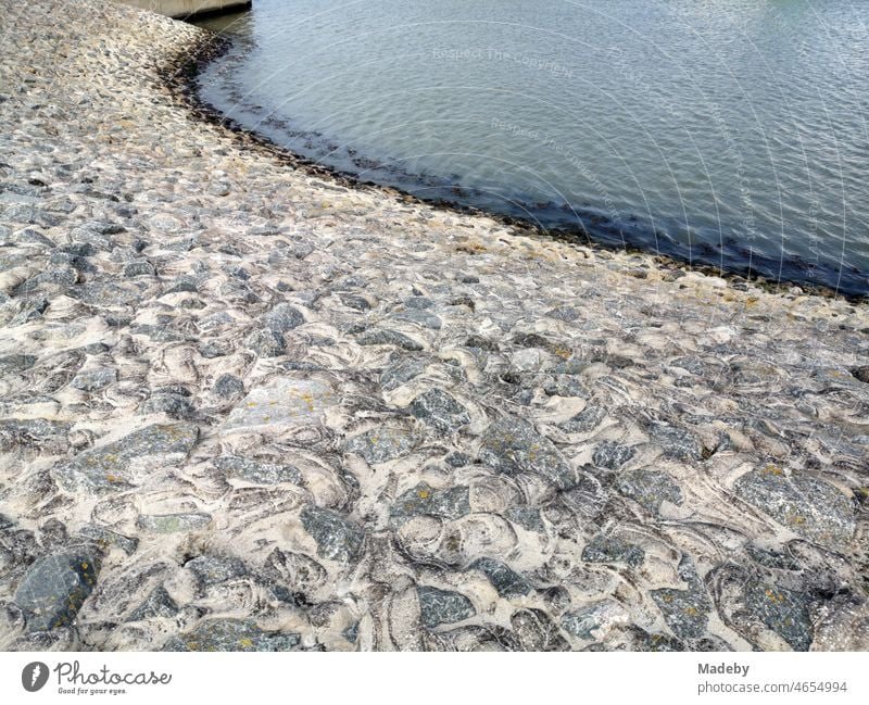 Massiver Küstenschutz mit Wellenbrecher aus Stein am Dach an der Hafenmole in Neuharlingersiel an der Küste der Nordsee bei Esens in Ostfriesland in Niedersachsen