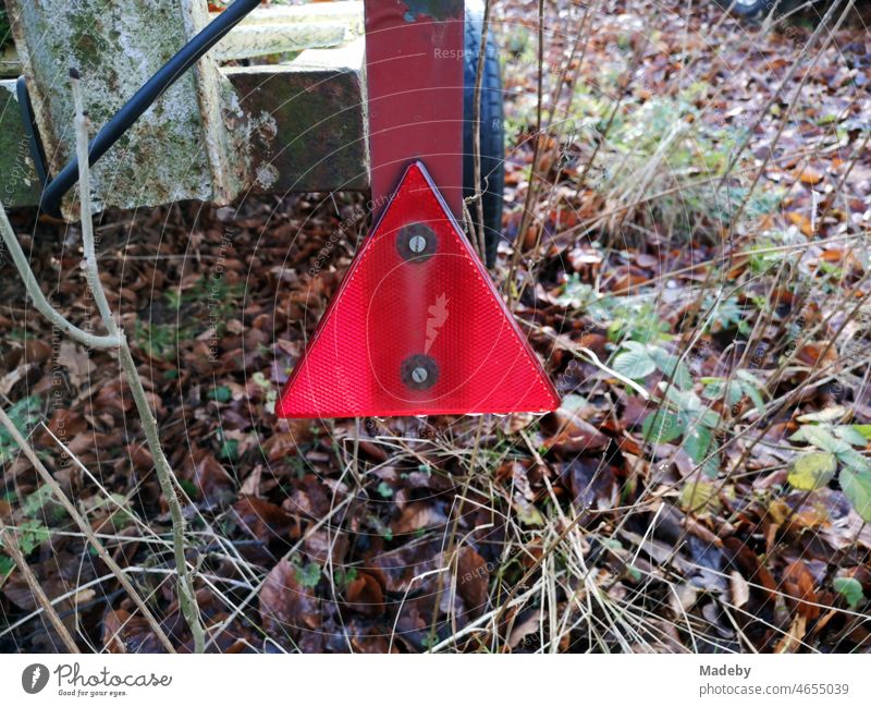 Dreieckiges rotes Katzenauge an einem ausrangiertem Bootsanhänger im Winter bei Sonnenschein im Teutoburger Wald in Oerlinghausen bei Bielefeld am Hermannsweg in Ostwestfalen-Lippe