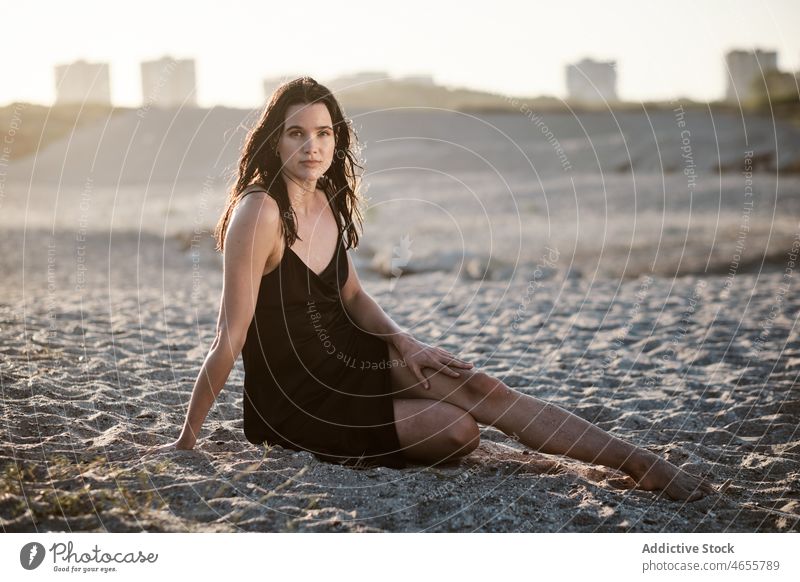 Schlanke attraktive Frau sitzt auf Sandstrand in sonnigen Tag wüst Sommer wolkenlos Blauer Himmel Barfuß Sonne Kleid Harmonie Sonnenkleid tagsüber Strand reisen