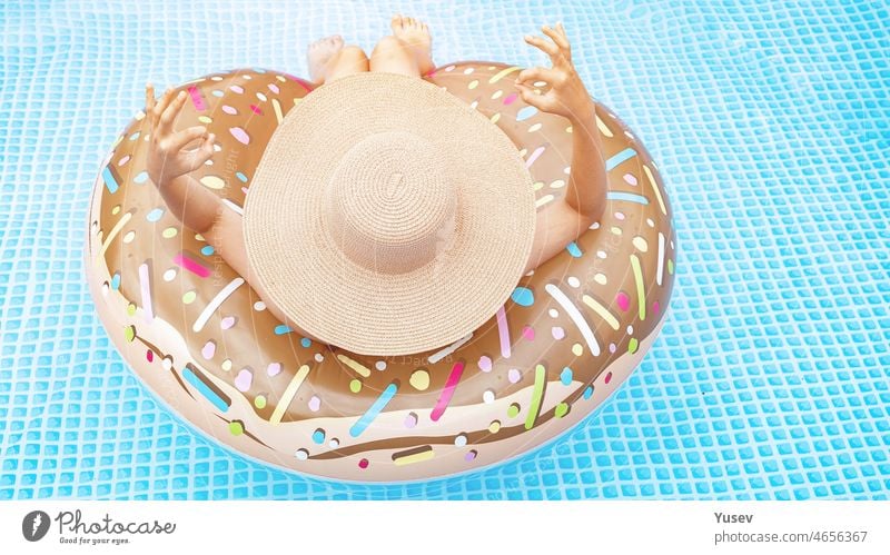 Schönes Mädchen in der in blauem Schwimmbad. Hübscher Teenager in einem Strohhut mit aufblasbarem Donut. Sommerurlaub Konzept. Rückansicht. Sommerferien-Konzept. WEB-Banner-Format. Platz zum Kopieren