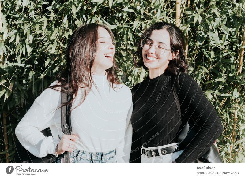 Porträt der lachenden glücklich Frauen High School Student außerhalb College-Gebäude mit einem grünen Gras Hintergrund. Happy Abschluss der Prüfungen feiern Konzept. Spaß beim Lernen