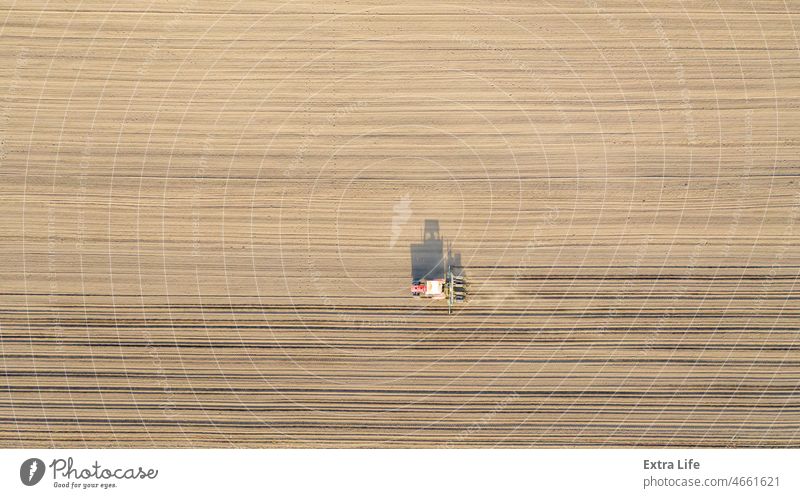 Luftaufnahme eines Traktors, der eine Sämaschine über ein landwirtschaftliches Feld zieht, Ackerland oben Ackerbau anbaufähig Müsli Mais Kornfeld Land Ernte