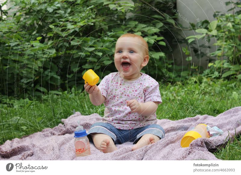 rothaariges Baby / Kleinkind sitzt auf einer Decke im Grünen und lacht strahlend lachen fröhlich glücklich Freude Kind Fröhlichkeit klein niedlich Glück