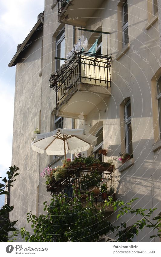 Sonnenschirm auf einem alten Balkon im stimmungsvollem Abendlicht Schirm Sonnenlicht Wetterschutz Schutz Sommer Erholung Altbau Balkone schmiedeeisern