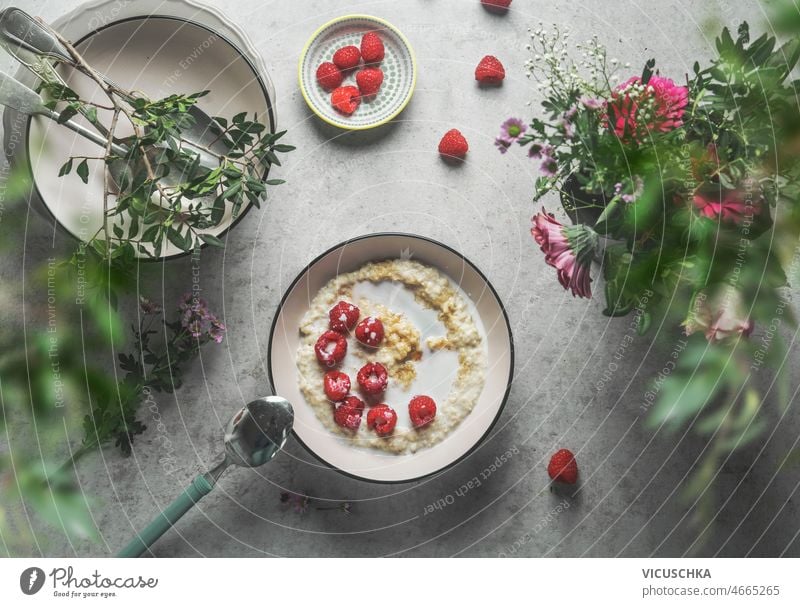 Hausgemachte Porridge-Schale mit Milch-Himbeeren am grauen Beton-Küchentisch selbstgemacht Haferbrei Schalen & Schüsseln melken Besteck schön Sommer Blumen