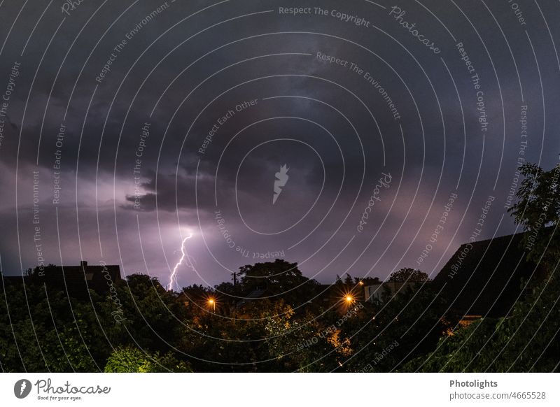 Donnerwetter! Ein Blitz am Nachthimmel. Im Vordergrund sind Hausdächer und Straßenlaternen zu sehen. Gewitter Gewitterwolken Unwetter Blitze dunkel Wolken