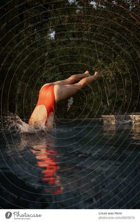 Was für ein erfrischender Start in den Tag, um in einen Swimmingpool zu springen. Ein wunderschönes Bademodell in einem roten Badeanzug tut genau das. Wenn es Zeit für die Ferien ist, scheint alles so viel leichter und frischer.