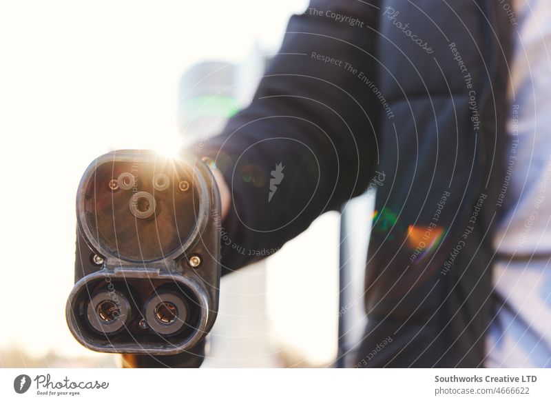 Mann hält Stecker für Elektroauto-Ladegerät Typ 1 an Ladestation Beteiligung elektrisch PKW Aufladen Station Sonnenlicht Tankstelle EV Schnellladegerät