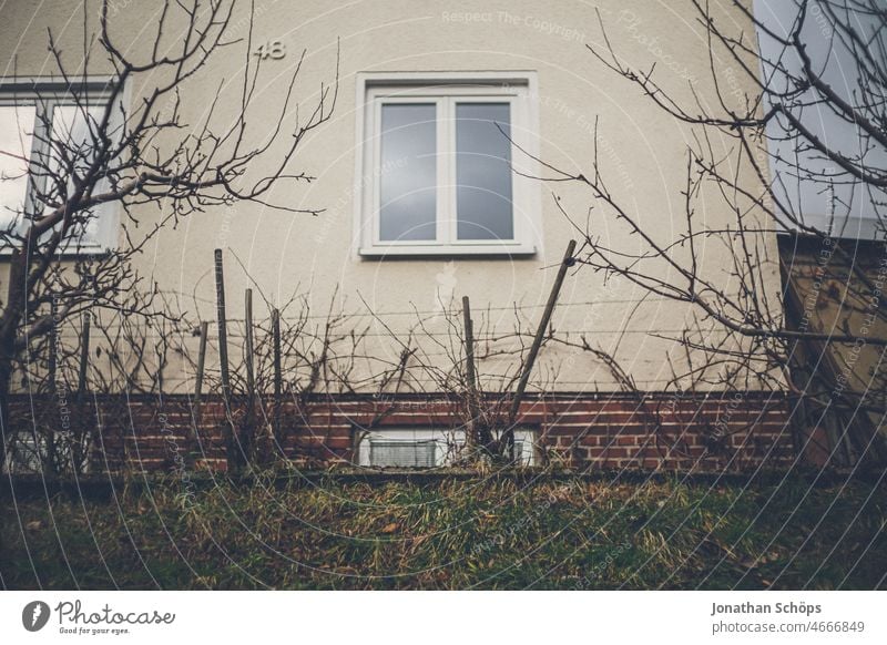 Hausfassade mit Vorgarten im Winter Fenster trist analog retro alt wohnen Wohnung Wohnhaus Fassade Miete Architektur fenster mietshaus wohnhaus mehrfamilienhaus