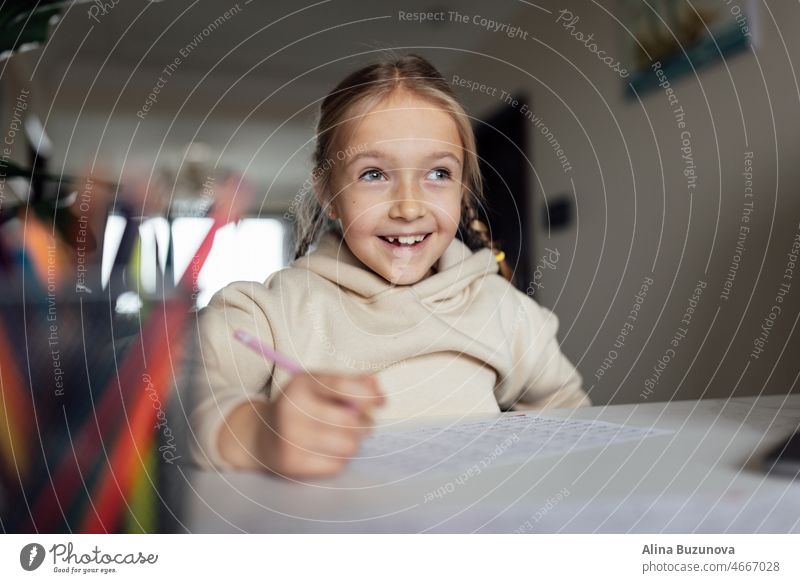 Kaukasisches Kind, das zu Hause online lernt und einen Laptop benutzt. Fernunterricht oder Fernstudium für Kinder. Hübsche, elegante Schülerin, die während der Coronavirus-Covid-19-Quarantäne und sozialer Distanzierung Hausaufgaben in Mathematik macht