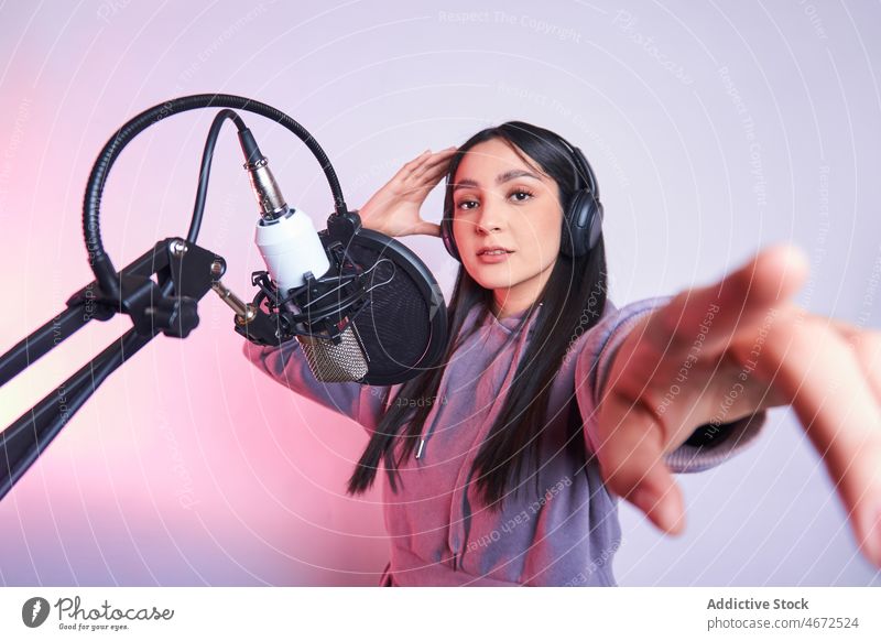 Frau singt im Studio ins Mikrofon Sänger singen Gesang Sängerin Kopfhörer Aufzeichnen Lächeln Musik Stimme Klang Glück Pop-Filter Erreichen feminin Vorschein