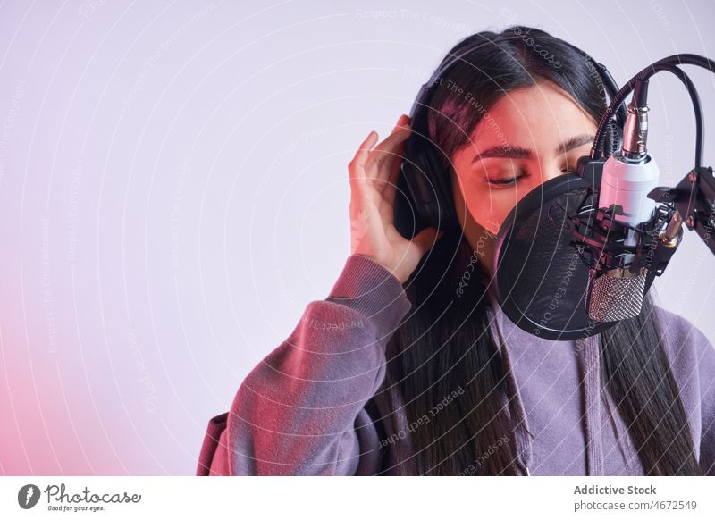 Frau singt im Studio ins Mikrofon Sänger singen Gesang Sängerin Kopfhörer Aufzeichnen Musik Stimme Klang lässig Pop-Filter feminin Vorschein jung Inhalt Atelier