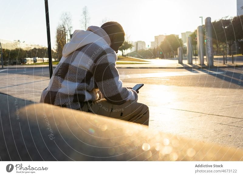 Schwarzer Mann durchsucht Smartphone auf der Straße Browsen online Textnachricht Stil Talkrunde Großstadt Internet modern lässig Stadt männlich schwarz Surfen