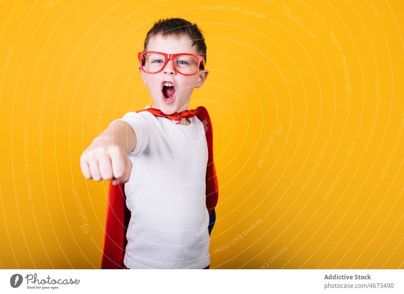 Verspielter Junge in Superhelden-Uniform, der so tut, als würde er fliegen Kind Flug Fliege die Faust ballen schreien Tracht Porträt Atelier Kraft Mut Held