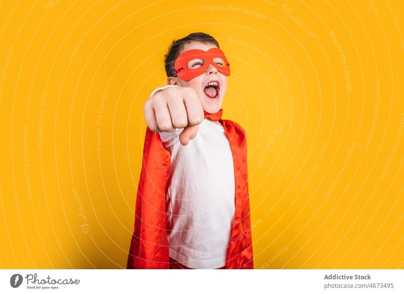 Verspielter Junge in Superhelden-Uniform, der so tut, als würde er fliegen Kind Mundschutz Flug Fliege die Faust ballen Tracht Porträt Atelier Kraft Mut Held