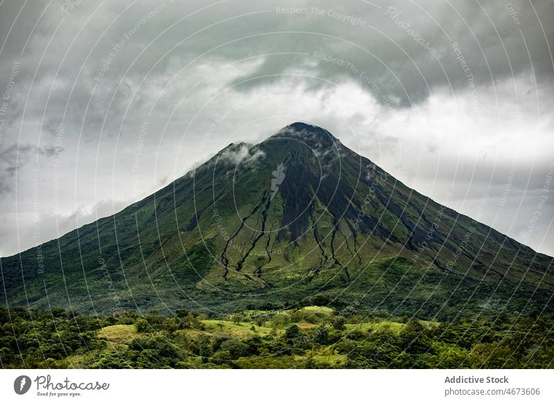 Grasbewachsener Vulkan gegen bewölkten Himmel Berge u. Gebirge Natur Feld bedeckt vulkanisch Landschaft wild Baum Gefahr Umwelt Flora grün Sommer wolkig Pflanze