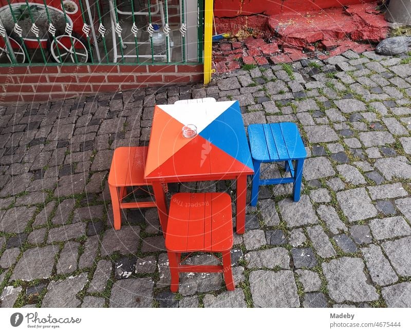 Bunte Hocker mit Tisch auf altem Kopfsteinpflaster vor einem Bistro, Teehaus und Café im Sommer in den Gassen der Altstadt von Bursa in der Türkei Stillleben