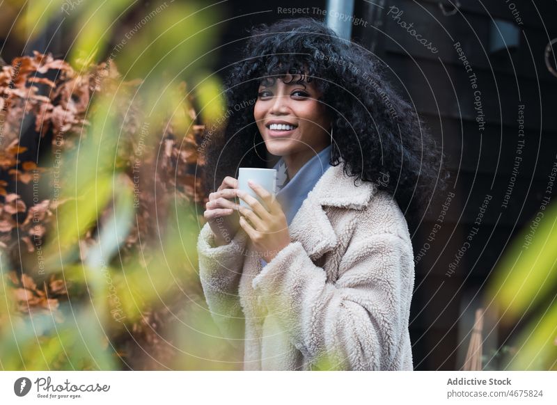 Lächelnde schwarze Frau mit einer Tasse Kaffee trinken sich[Akk] entspannen ruhen Haus heimwärts Kälte Kaffeepause warm afroamerikanische Frau Becher